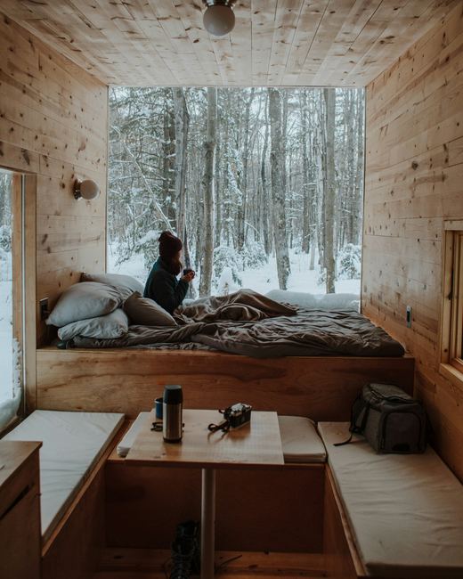A bedroom under a pitched timber roof, snow through the window
