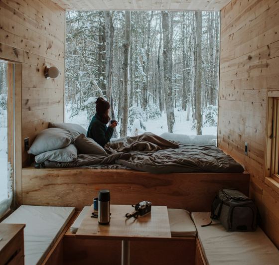 The bed under a full-height window looking into snowy woods