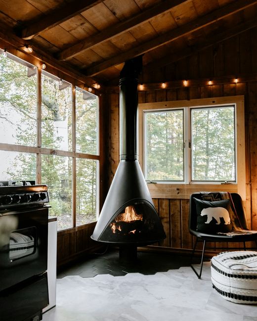 The main room — suspended wood stove, windows into the oaks