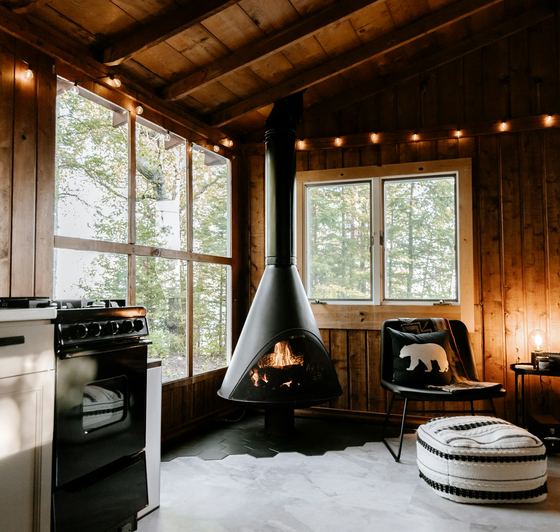 The main room — suspended wood stove, windows into the oaks