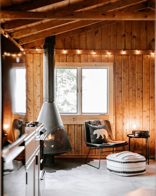 A cabin interior with a stone fireplace and timber ceiling