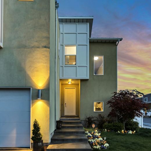 The house from the street at dusk, lit steps up to the door