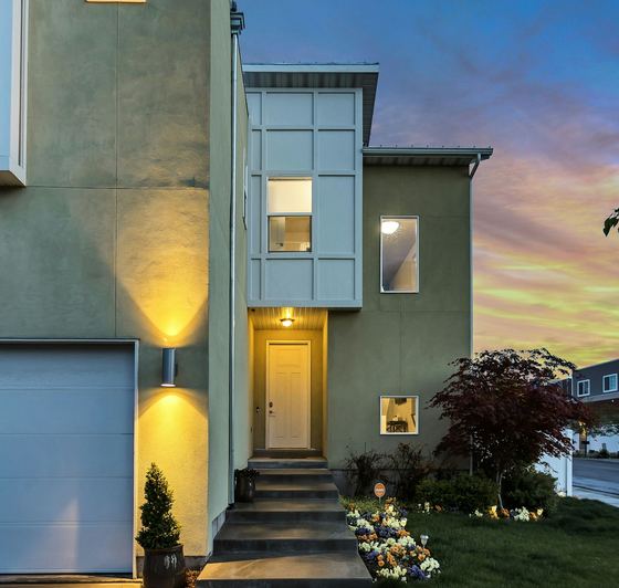 The house from the street at dusk, lit steps up to the door