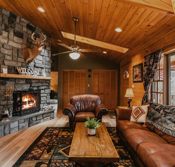 The living room — stone fireplace lit, leather sofas under a vaulted pine ceiling