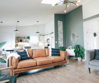 The open-plan living and kitchen end, teal wall and a tan sofa