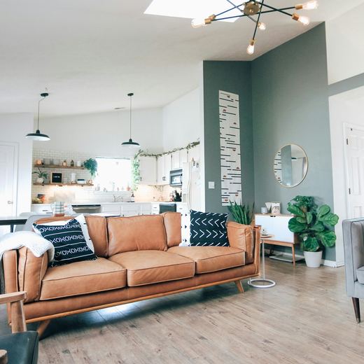 The open-plan living and kitchen end, teal wall and a tan sofa