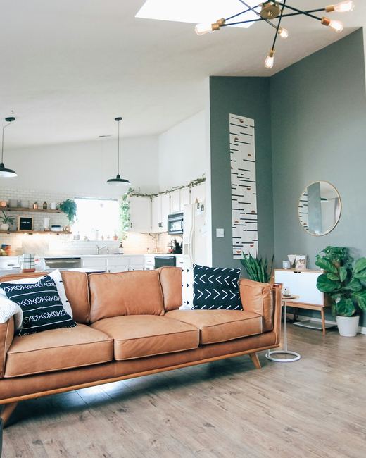The open-plan living and kitchen end, teal wall and a tan sofa