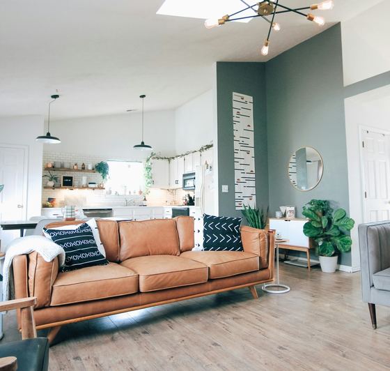 The open-plan living and kitchen end, teal wall and a tan sofa