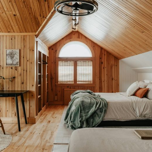 The bedroom under the pitched pine ceiling, desk by the arched window