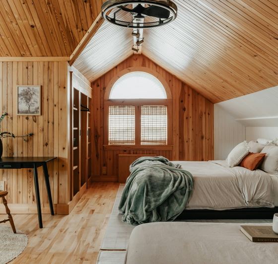 The bedroom under the pitched pine ceiling, desk by the arched window