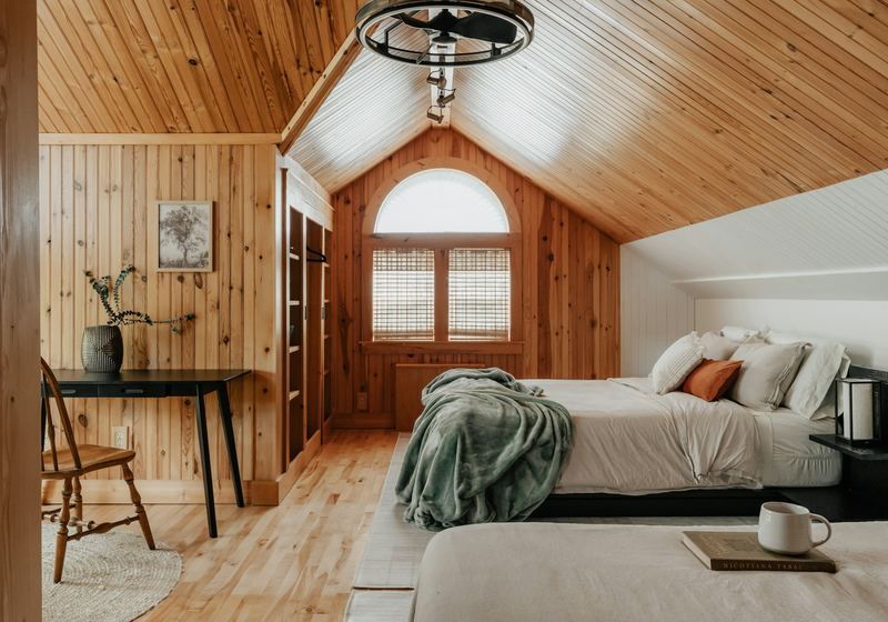 The bedroom under the pitched pine ceiling, desk by the arched window